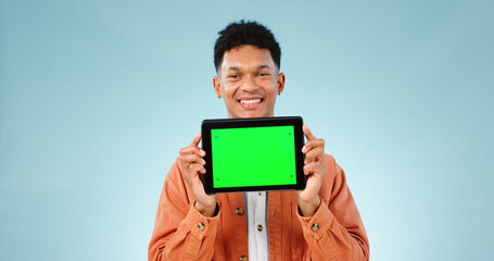 Portrait, smile and man with tablet, green screen and promotion on a blue studio background. Face, person and model with technology, internet and presentation with mockup space, news and digital app