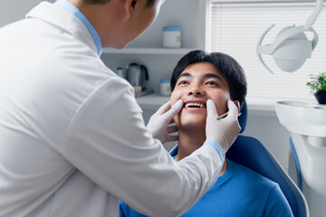 Young man getting dental checkup at dentistry. Dentist using dental equipment for examination of teeth of patient.