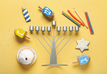 Hannukah composition with menorah, candles and dreidels on yellow table