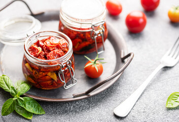 Jars with sun dried tomatoes with fresh herbs and spices. - obrazy, fototapety, plakaty
