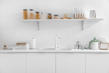White counters with sink and utensils in interior of modern kitchen