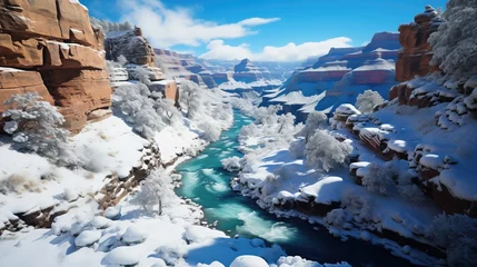 Deurstickers A snowy river cuts through a canyon with layered rock formations under a clear blue sky. © DigitalArt