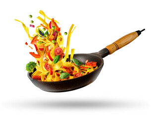 Cooking Italian pasta with vegetables flying over a hot frying pan isolated in white.