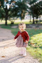 Little surprised girl walks along a dirt path in the park