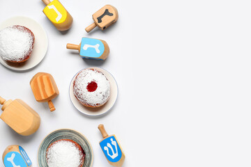 Hanukkah composition with dreidels and donuts on white background
