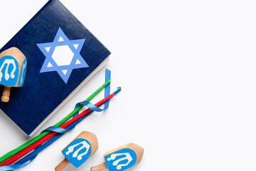 Hanukkah composition with Torah, candles and dreidels on white background