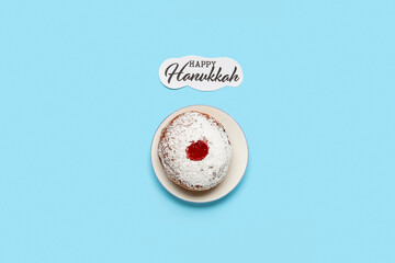 Tasty donut with jam and text HAPPY HANUKKAH on blue background