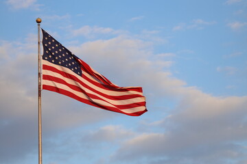 United States flag with blue sky and clouds in the background