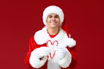 Santa Claus with candy canes on red background