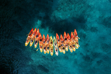 Row of colorful kayaks stands in the sea. Drone