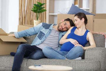 Fototapeta premium upset pregnant couple lost apartment things packed in boxes
