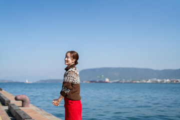 Fototapeta na wymiar 海を散策するニットを着た女性
