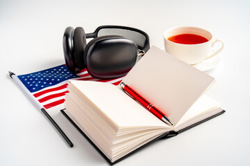 Notepad with USA flag and headphones on white background. English language audio courses educational concept
