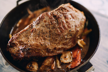 Baked roast beef with vegetables is in a frying pan. Top view