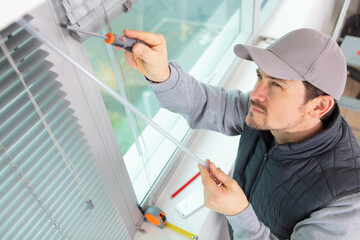 man installing window blinds using screwdriver