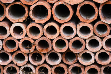 Drainage old clay pipes for sewage stacked in a texture with holes