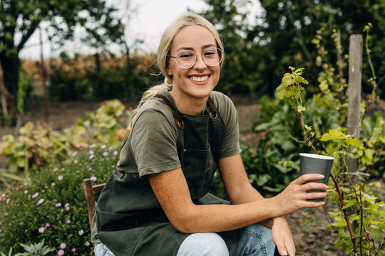 Happy woman sitting in the garden and looking at the camera.