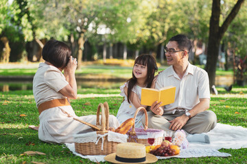 Mother takes a picture of the father and daughter enjoying their time together in the summer outdoors at the park.