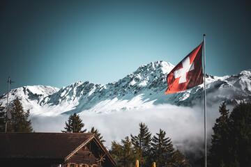 Wechsel der Jahreszeiten, vom Herbst zum Winter in den Schweizer Alpen mit Schweizer Fahne, Lenzerheide - obrazy, fototapety, plakaty