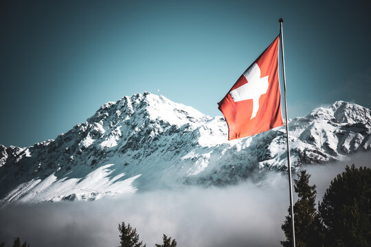 Wechsel der Jahreszeiten, vom Herbst zum Winter in den Schweizer Alpen mit Schweizer Fahne, Lenzerheide