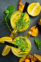 Refreshing lemonade with lemon and rosemary with ice. On a dark stone table. Drinks