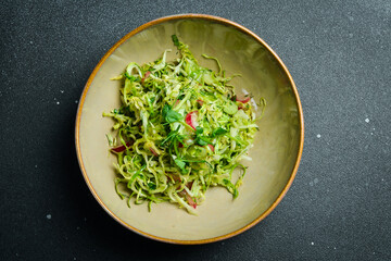 Healthy food. Fresh cabbage salad, radishes with olive oil. On a plate. Restaurant serving. Close up. On a dark stone background.