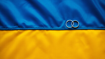 Wedding rings lie on the flag of Ukraine. Panoramic view