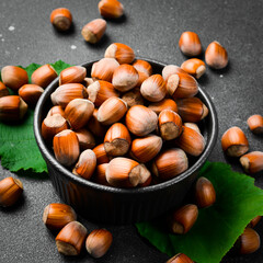 Hazelnuts in a black stone bowl. Side view. Full frame of heap of hazelnuts. Close up.