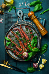 Cooked octopus tentacles with garlic and basil. Delicious healthy traditional food closeup served for lunch in modern gourmet cuisine restaurant.