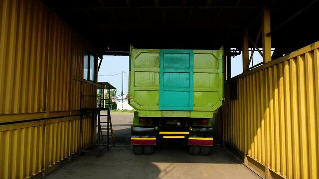 Process of pouring aggregate on a truck. Truck approaches the mixer machine for the process of pouring the mixed and homogenized aggregate into the transport truck at the Asphalt Mixing Plant factory.
