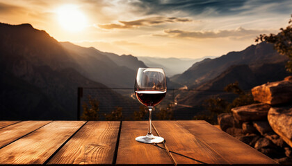 a glass of red wine on a table in front of a mountain range - obrazy, fototapety, plakaty