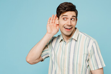 Fototapeta premium Young smiling happy man he wears striped shirt casual clothes say hush be quiet with finger on lips shhh gesture isolated on plain pastel light blue cyan background studio portrait. Lifestyle concept.