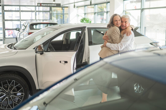 Mature Caucasian couple hugging. Elderly man and woman buying a new car. 