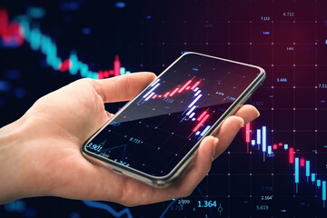 Close up of female hand holding cellphone with falling forex chart on blurry grid background....