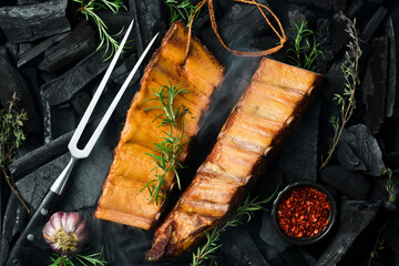 Smoked pork ribs with spices on a stone background. On a black stone background. Free space for the...
