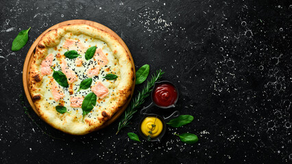 Pizza with salmon, cheese and spinach. classic pizza On a black stone background. Top view.