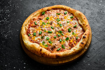 Pizza with tuna, corn and cheese. classic pizza On a black stone background. Top view.