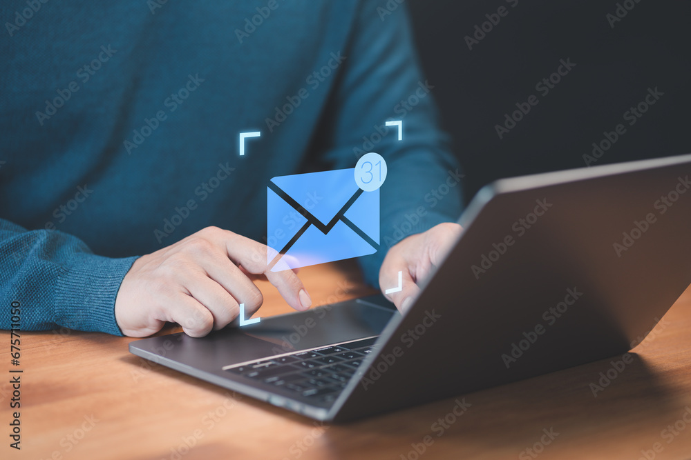 Aufkleber Male hand using a computer laptop typing on keyboard and surfing the internet on office table with email icon. Concept of Email marketing, send e-mail or news letter, online working internet network.