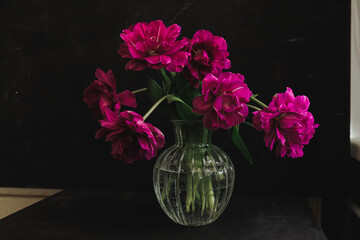bouquet of dark red lilac tulips in glass vase on dark background. flower bouquet in vase on table. Gift interior decoration. florist, decorator. Flower shop.