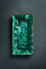Green creative rectangular plate for serving food. On a black stone background. Free space for text.