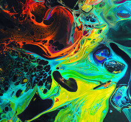 Colorful mix of neon paints swirling on black surface