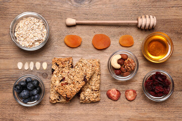 Tasty granola bars served on wooden table, flat lay