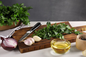Fresh green parsley and different products on white wooden table