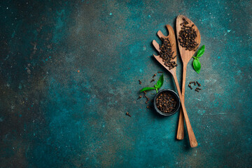 Fragrant cloves in a wooden spoon. Spices and condiments. Top view. On a dark textured background.