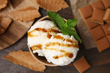 Scoops of tasty ice cream with caramel sauce and mint on wooden table, flat lay