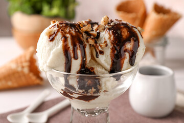 Tasty ice cream with chocolate topping and nuts in glass dessert bowl on table, closeup