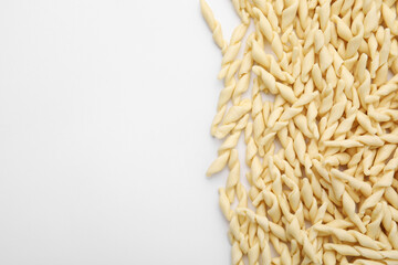 Uncooked trofie pasta on white background, flat lay. Space for text