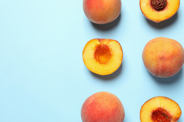 Cut and whole fresh ripe peaches on light blue background, flat lay. Space for text