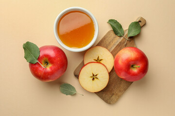 Delicious apples, bowl of honey and leaves on beige background, flat lay