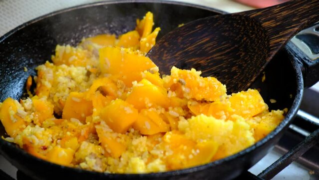 Cooking pan with fried chopped pumpkin, carrot, cereal, vegetable. Process cooking